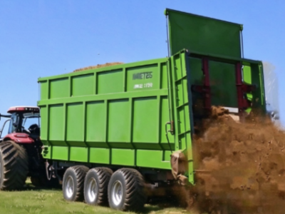 Imetec trailed solid manure spreader working in farmland, spreading organic manure evenly on pasture
